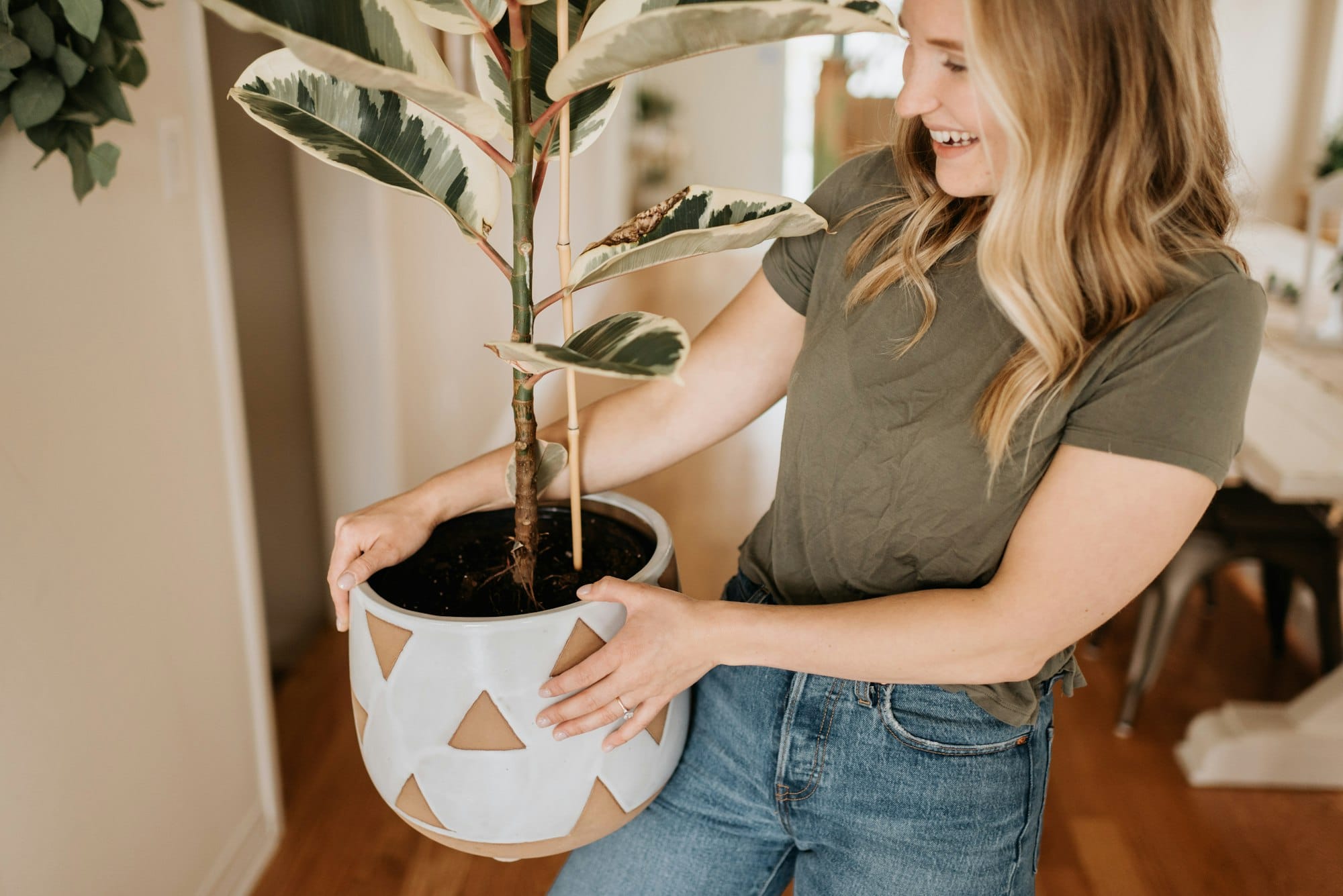 Woman smiling and carrying large pot of house plant